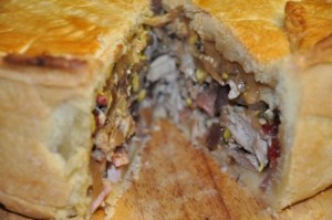 An image of turkey and bacon pie with a slice removed