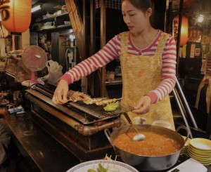 An image of a lady cooking on a Yakitori grill in Japan