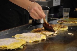 An image of Okonomiyake being glazed with sauce.