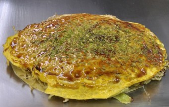An image of Japanese Okonomiyake on a hotplate.