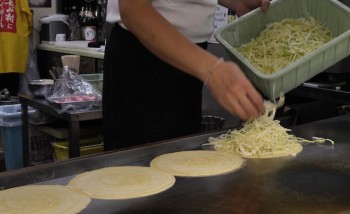 An image of a chef adding shredded cabbage for Okonomiyake filling.