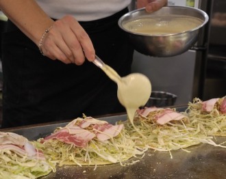 An image of Okonomiyake cooking on a hotplate in Japan.