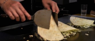An image of Okonomiyake being flipped on hotplate.