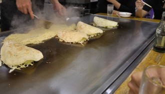 An image of soba noodles being added to Okonomiyake.