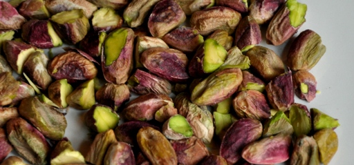 An image of raw pistachio nuts on a plate.