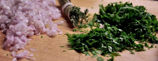 An image of chopped shallots and parsley on a board