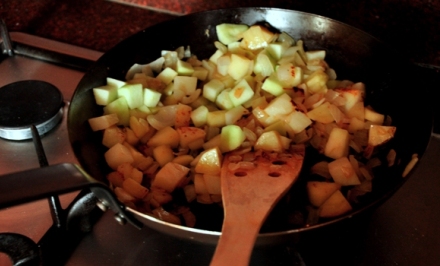 An image of onions, apples and potato in a pan