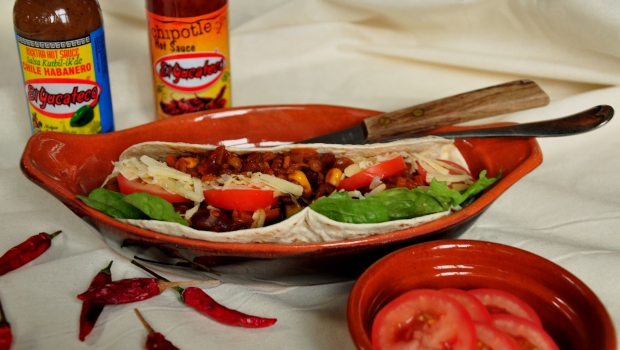 An image of vegetarian chilli in a soft taco with tomatoes