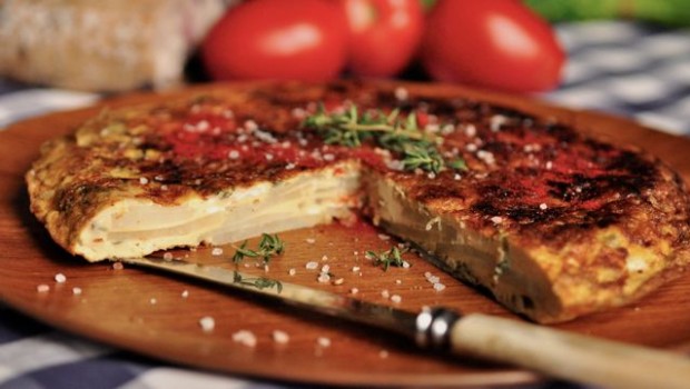An image of a sliced Spanish tortilla with tomatoes