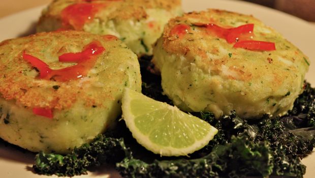 AN image of green fishcakes on a bed of kale with chilli sauce