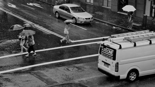 An image of pedestrians crossing a Sydney road in the rain