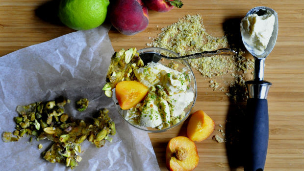 Coconut ice cream with pistachio praline and peaches on a board